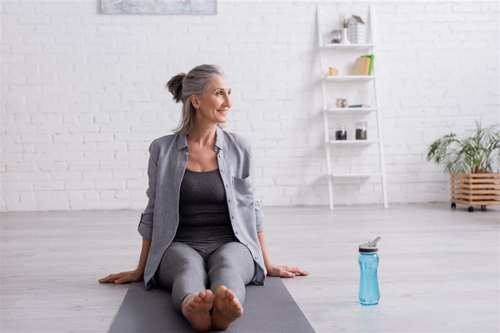 Frau in entspannter Sitzhaltung auf einer Yogamatte